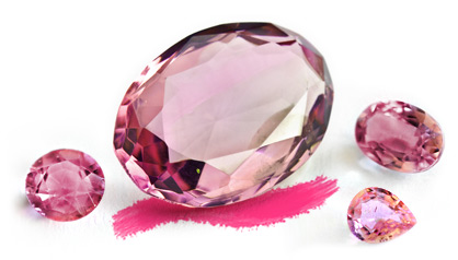 A pink faceted oval-shaped gemstone surrounded by smaller pink tourmaline specimens
